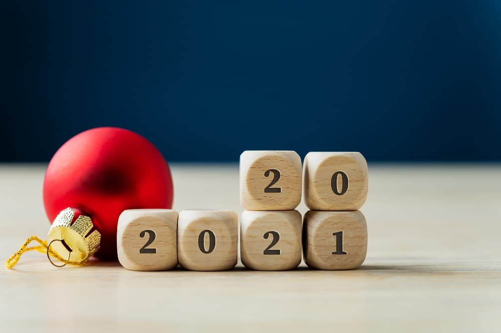 Red holiday bauble next to a 2021 sign on wooden dices with number 20 on top.